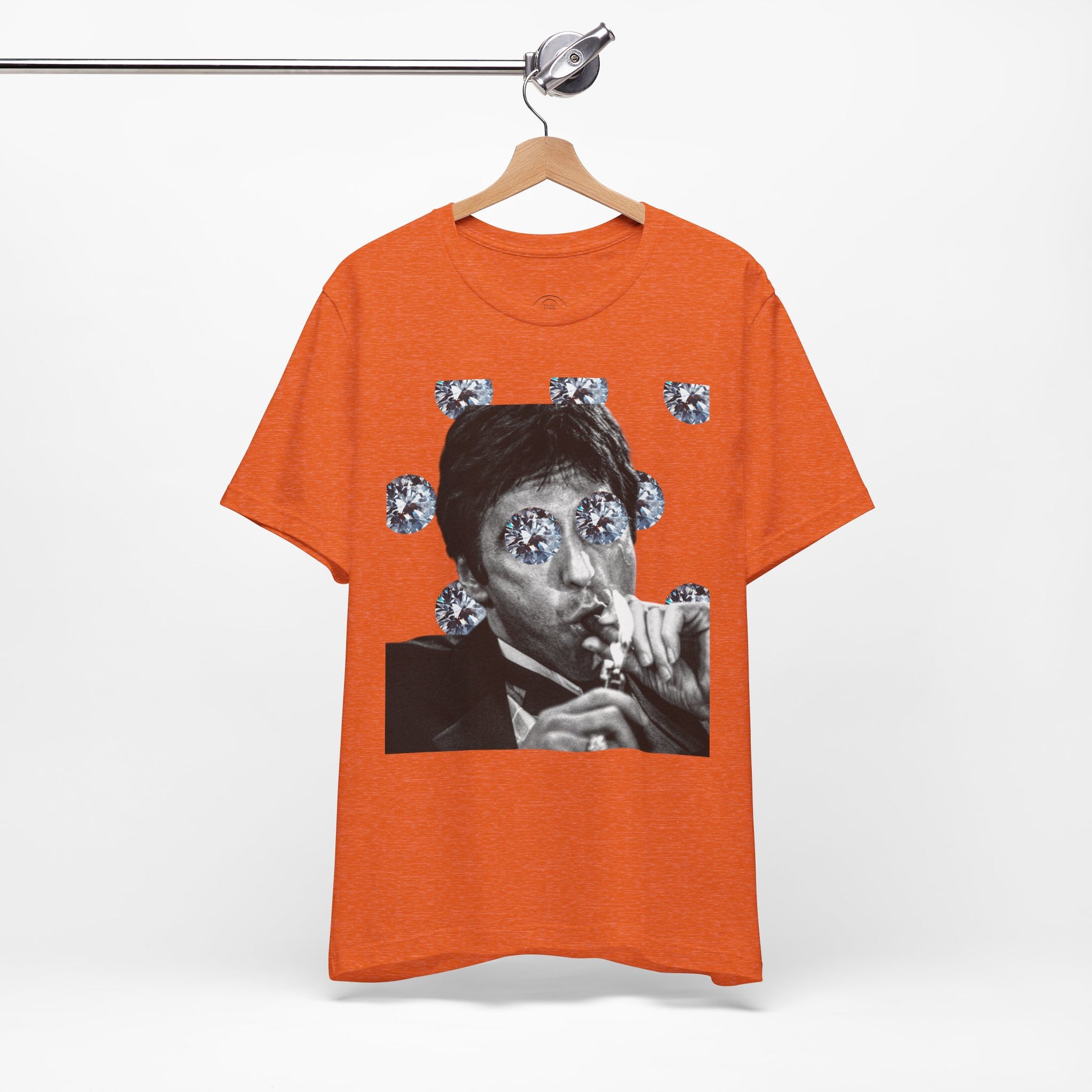 Orange t-shirt with a graphic design on a hanger against a white background